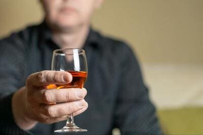 мужчина держит стакан с алкоголем