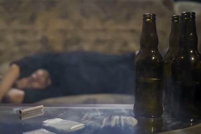 Пустые пивные бутылки и пьяный мужчина